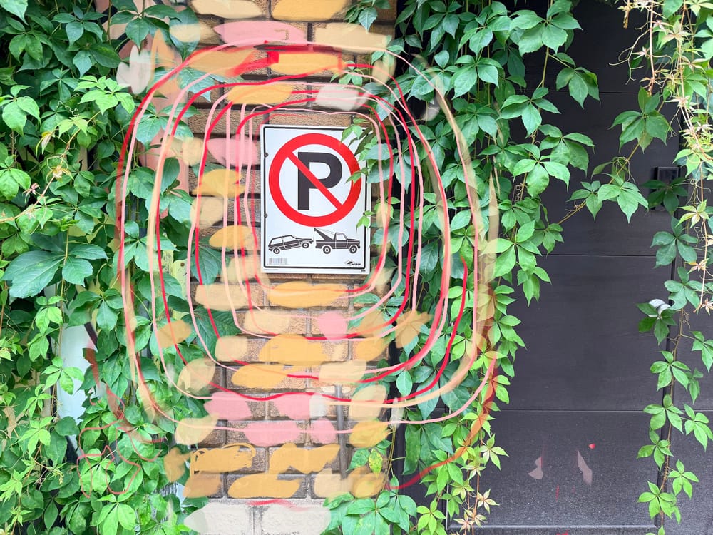 No parking sign with tow truck towing a car and ivy covering a wall plus doodles on top of everything.