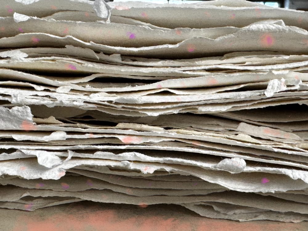 A pile of handmade paper with some colourful painting on top
