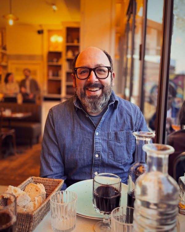 Andrew Boardman eating bread and drinking wine in a Paris cafe